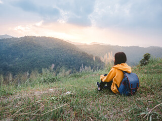 woman hiking with backpack relaxing in nature and enjoy the sunset view on mountain peak at Mae Wong national park Thailand.