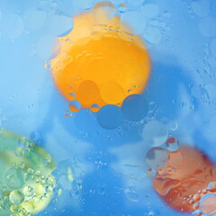 Oil drops in water. Abstract background with colorful splashes orange and red on a blue background. Modern Art.