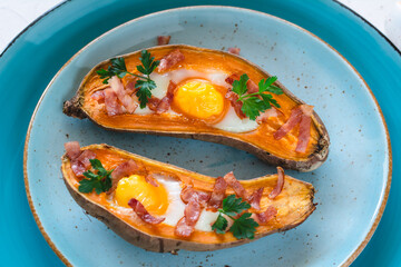 Baked sweet potato with fried egg, bacon and parsley.