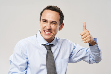 happy guy in shirt and tie shows positive gesture and smiles on light background