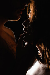 lighting on man touching lips of sexy woman isolated on black.