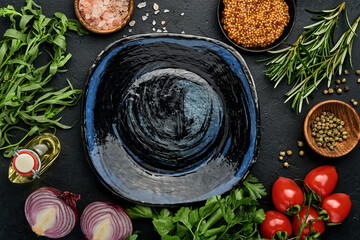 Fresh tarragon. Branch of fresh herb seasoning and cooking products, tomatoes, peppers, onions and olive oil on black concrete background. Cooking Background. Top view.