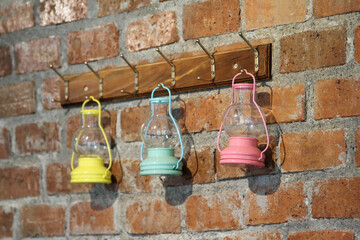 Three oil lamps hanging on brick wall.