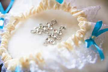 A pair of silver earrings, white garter with blue bows