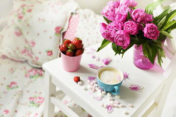 A bouquet of pink peonies and coffee with milk on a table in a bright room in the Provence style. Delicate cute still life.