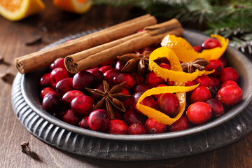 Ingredients for making mulled wine with cranberries. Orange, cinnamon, cranberry berries, cloves,...