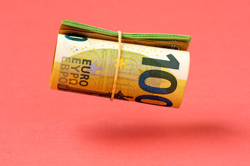 Roll of euro currency levitating over pink background - obrazy, fototapety, plakaty