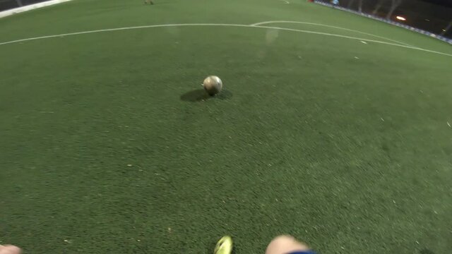 Point of view of soccer player training his skills at football field at evening time. Man practicing dribbling the ball and kicking it to opponent. Guy passes the ball to friend. Leisure concept. POV