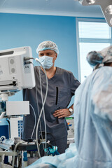 Anesthesiologist keeping track of vital functions of the body during cardiac surgery. Surgeon looking at medical monitor during surgery. Doctor checking monitor for patient health status.