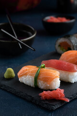 Rainbow Sushi Roll and nigiri with salmon, tuna, avocado and vegetables placed on black rock.Japan restaurant menu.Japanese food.