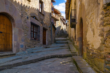 Fototapeta na wymiar View of Fossar street, one of the most typical streets of the medieval center of Rupit where all the houses have the aesthetics of the medieval centuries. Catalonia, Spain