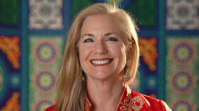 Extreme closeup portrait of a pretty blond haired woman happy smiling looking at camera wearing ethnic clothes on ethnic arabic or Turkish background. Happy mature woman enjoys life.