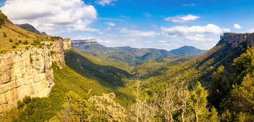 Fototapeta na wymiar Great panoramic view of the Guillerias guarded by the impressive cliffs of Collsacabra. Guillerias y el Collsacabra natural park, Catalonia, Spain