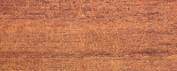 A wall of old, darkened bricks. Wide panoramic horizontal texture.