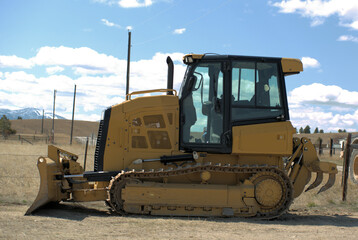 Heavy equipment road grader at rest on a rural road.