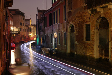 Venice, light trails of a boat on a small canal in Castello, Italy