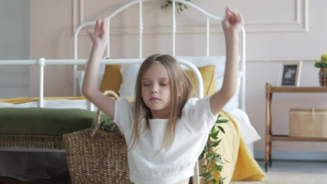 Little cute baby girl doing yoga exercise, performing yoga meditation breathing technique at home. Kid girl sitting in lotus position, closed eyes and meditate. Happy Kid girl dancing, enjoy childhood