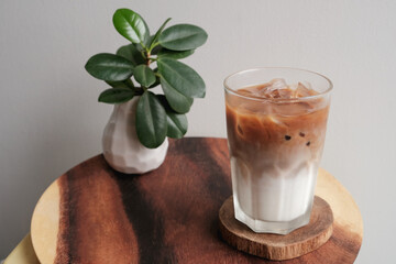 A glass of iced coffee latte on wood plate