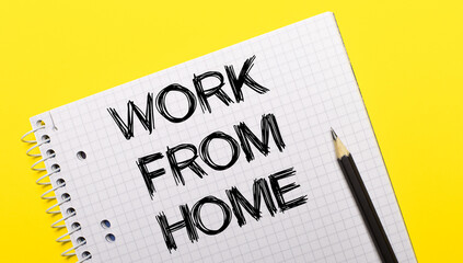 White notebook with inscription WORK FROM HOME written in black pencil on a bright yellow background.