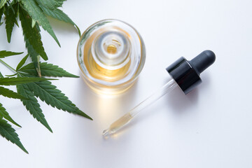 Medicinal hemp leaves next to a dropper and a glass bottle of CBD hemp oil top view. Medical cannabis concept