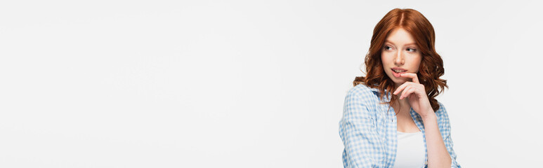 Fototapeta premium pensive redhead young woman in blue checkered shirt looking away isolated on white, banner.