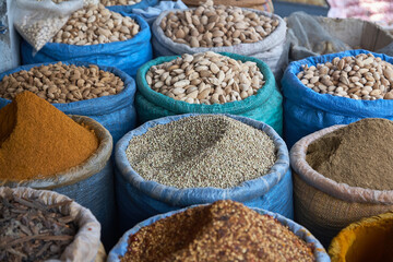Coriander seeds, almonds, turmeric and other spices at a market in blue bags. Normal perspective. Daytime shot. 