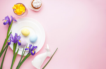 Easter holiday table setting and plates with colorful eggs on a pink background. Top view, space for text.