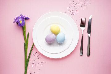Easter table with daffodil and cutlery on a pink background. Top view, place for text.