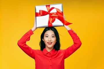 Obraz na płótnie Canvas woman with gift box above her head on yellow background celebration birthday model