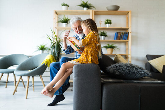 Grandparent Enjoy Spending Time Laughing With Little Girl Grandchild At Home