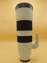 The telephoto lens is gray for the camera . Yellow background. Macro photography.