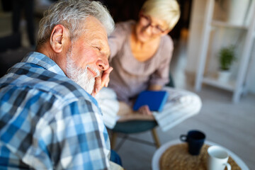 Mature couple relaxing at home and reading book together