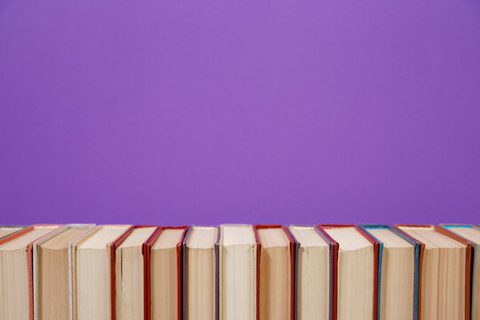 Composition with vintage old hardback books, diary, fanned pages on wooden deck table and colored background. Books stacking. Back to school. Copy Space. Education background.