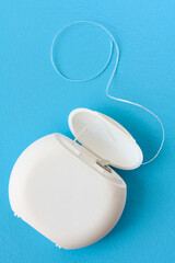Container with dental floss close up on blue background