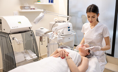 Beautiful woman receiving face oxygen peeling at cosmetology center. Cosmetology and professional...