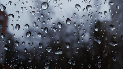 Raindrops on the window macro photo with selective focus. Water splashes in the city during the storm.
