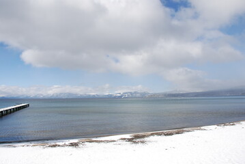 Calm winter day in Lake Tahoe with the pier and snow. 