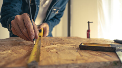Male carpenter builder working with wooden board in the workshop to decorate the woodwork.