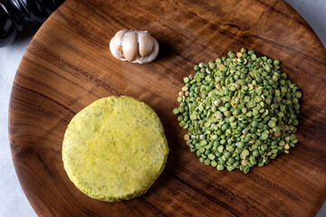 vegan and vegetarian pea burger with raw peas scallion garlic purple onion pepper on wooden plate for healthy eating