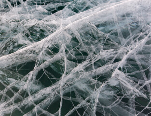 Frozen Baikal lake with cracks and methane bubbles on the transparent ice surface. Winter abstract and blue ice background.
