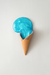 Ice cream cone with turquoise slime on grey background. Summer minimal concept. Flat lay.