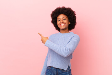 afro black woman looking excited and surprised pointing to the side and upwards to copy space