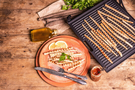 Grilled scorzonera with sauce on old wooden table