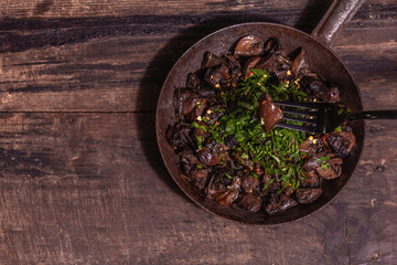 Fried royal champignons in an old cast-iron skillet with trendy hard light, dark shadow