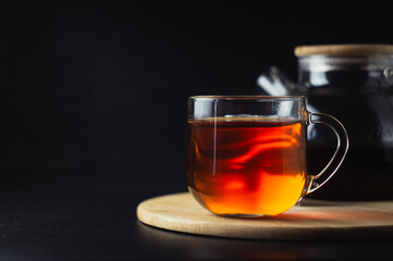 A mug of black tea stands on a wooden stand