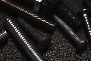 Scattered bolts on table dark background