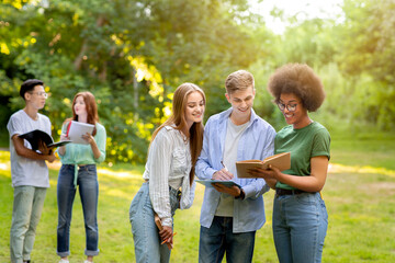 Multi-ethnic college students resting outdoors after classes, chatting and enjoying time together