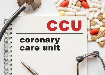 Page in notebook with coronary care unit CCU on white background with stethoscope and group of...