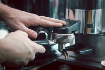 Fototapeta na wymiar Close up of barista hands preparing hot coffee, waiter staff working with coffee machine in coffee shop counter bar.