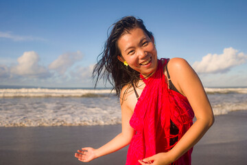 Fototapeta na wymiar Summer lifestyle portrait of young happy and attractive Asian Japanese woman in traditional sarong at beautiful beach enjoying holiday trip to tropical island